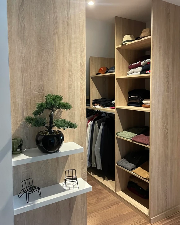Dressing moderne avec armoires en bois naturel aux portes coulissantes ouvertes révélant rangements intérieurs, étagères et penderies