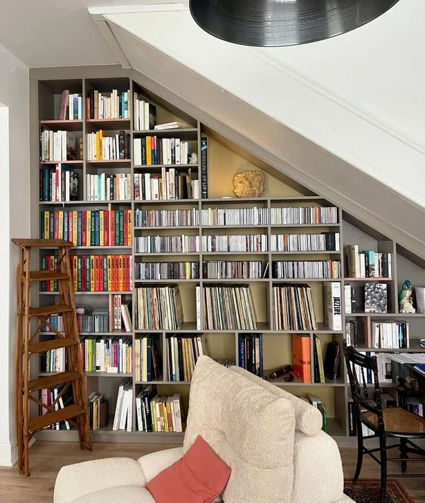 Intérieur d'atelier artisanal avec étagères en bois brut contenant une collection de livres anciens reliés cuir, carnets et albums photo vintage