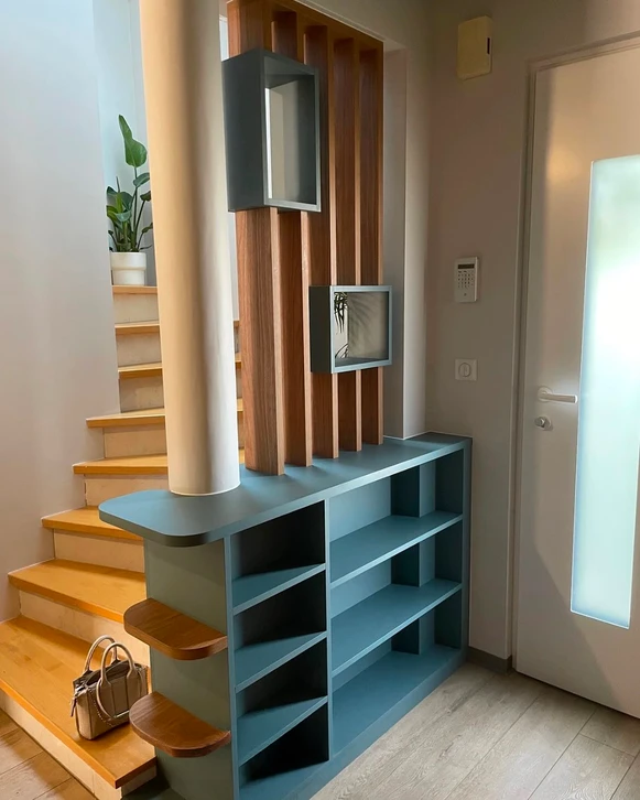 Espace de travail moderne sous escalier avec bureau d'angle blanc, chaise ergonomique, rangements modulaires intégrés et bibliothèque