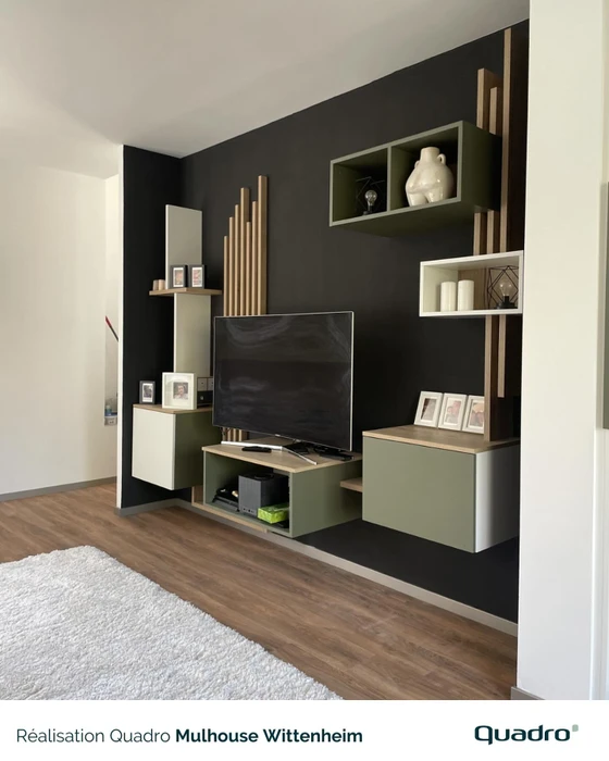 Salon moderne avec canapé gris modulaire, bibliothèque en bois intégrée séparant l'espace cuisine