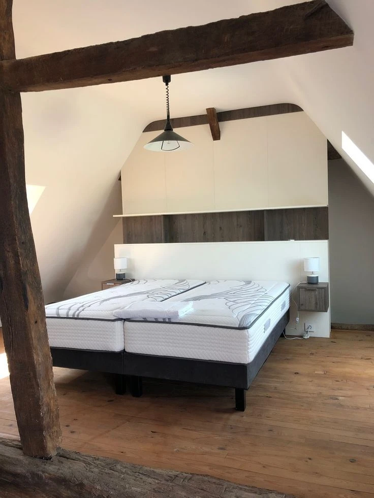 Chambre moderne avec lit coffre à mécanisme de levage hydraulique ouvert, révélant l'espace de rangement intérieur et le sommier à lattes en bois